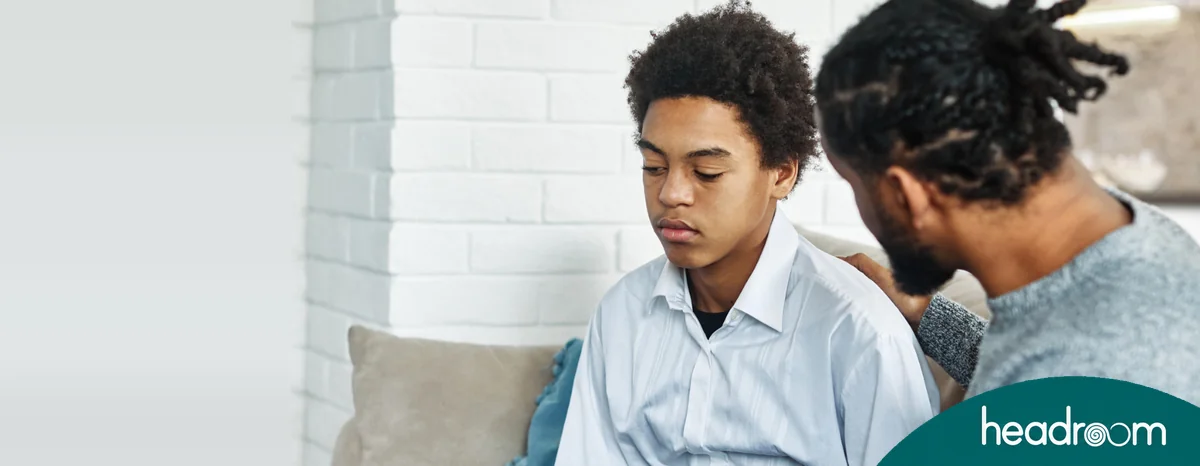 Father comforting his worried school-age son, illustrating parental support for children facing bullying and harmful peer pressure.